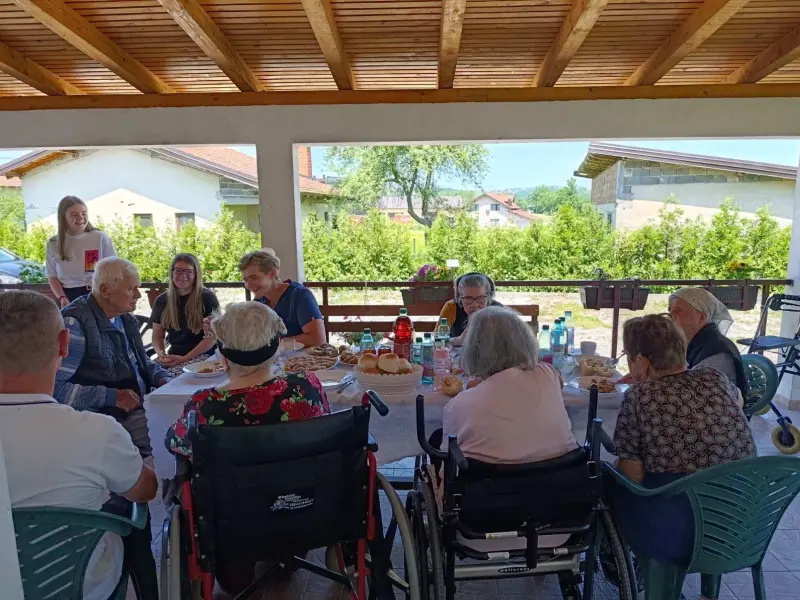 Korisnici i osoblje doma tokom zajedničkog obroka na terasi